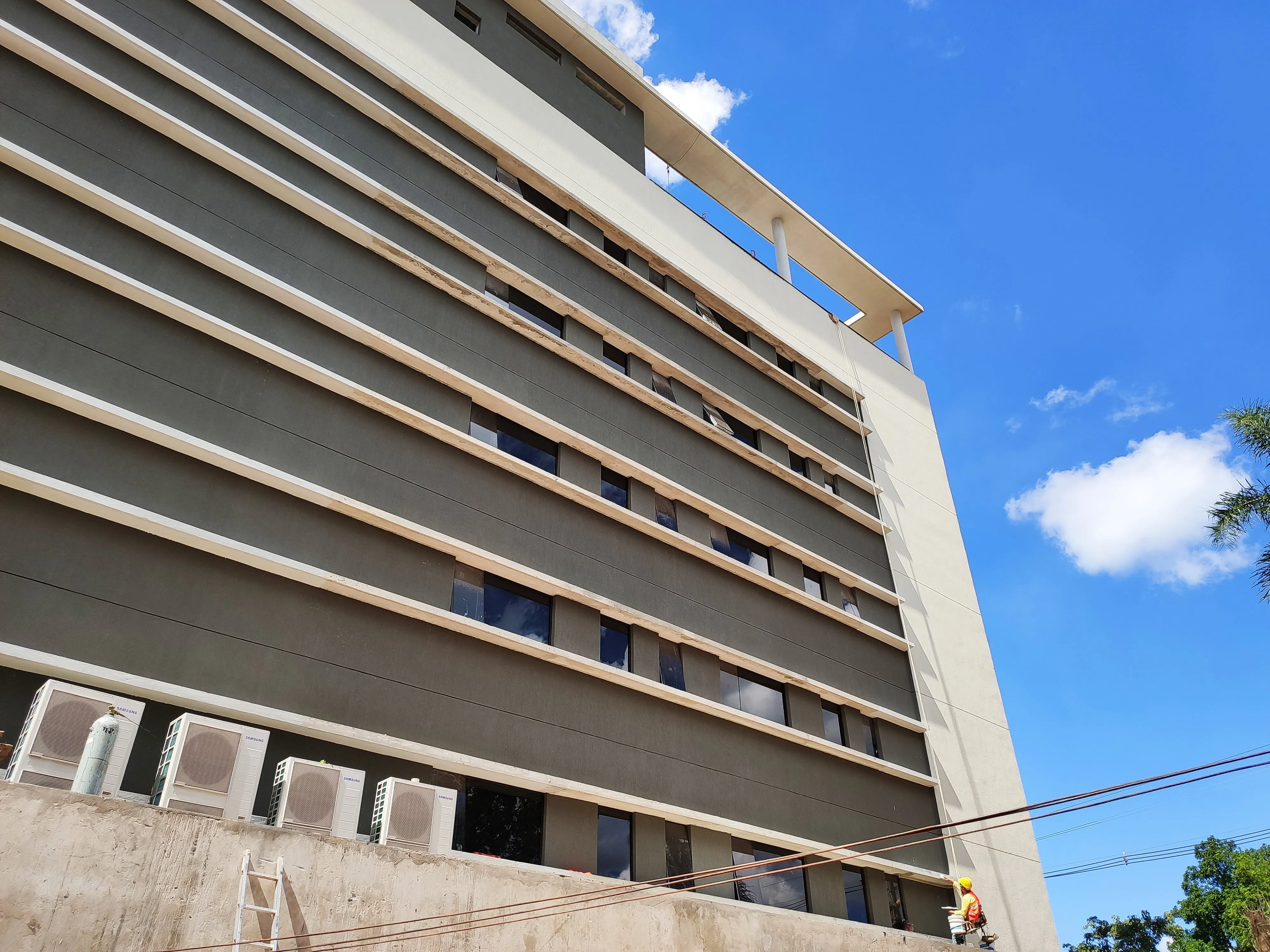 Fachada de un edificio de siete plantas en obra, con el sistema de climatización en instalación.